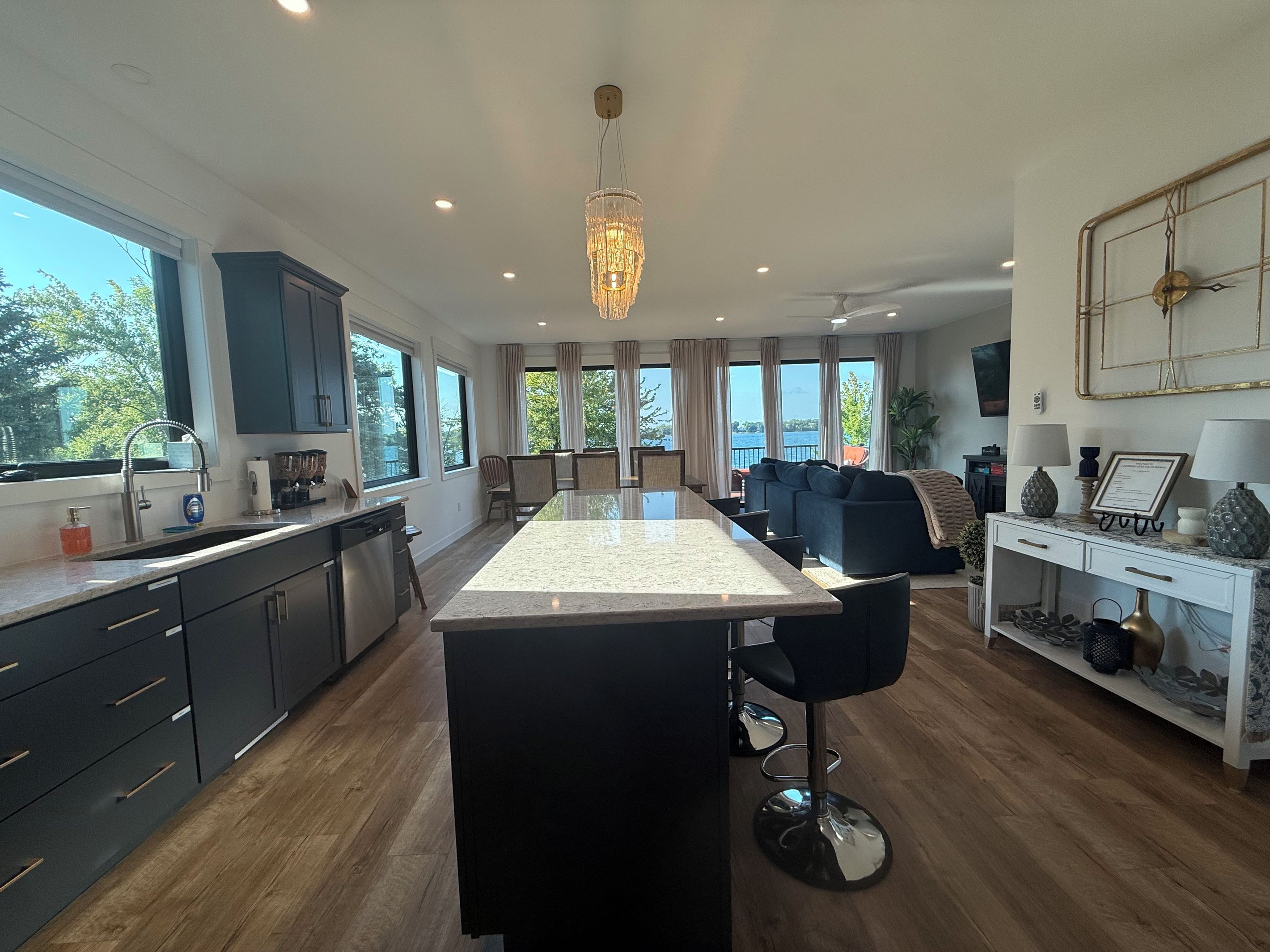 A modern kitchen with a central island, dark cabinetry, and a view to the outside.