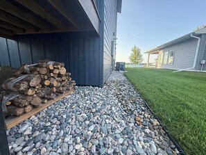 A building exterior with a gravel pathway leading to a wooden pile of logs. - Lakeside Luxe on Pickerel (Richville)