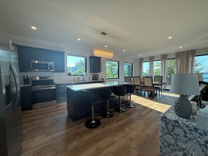 Una cocina moderna con una isla central, muebles oscuros y un comedor con vistas.