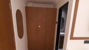 A hallway with a wooden wardrobe, a circular mirror, and a tiled floor. - Airavat (Bhubaneshwar)
