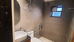 A bathroom with a toilet, sink, and mirror. - Airavat (Bhubaneshwar)