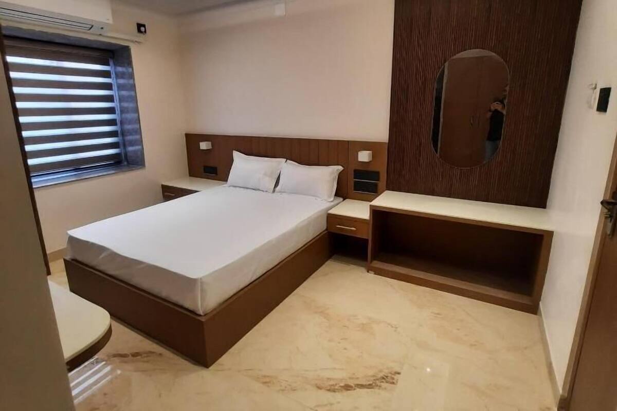 Una habitación de hotel moderna con una cama grande, mesitas de noche, un escritorio integrado y un espejo en la pared.