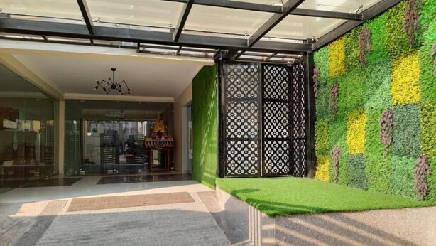 A modern interior with a glass partition, a green wall with a pattern, and a small grassy area. - Airavat (Bhubaneshwar)