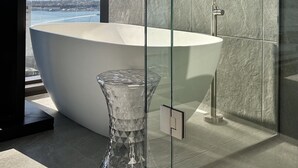 A modern bathroom with a freestanding bathtub, a glass vase, and a view of a body of water. - High-Rise Luxury Stay with Harbour Views – 51 Albert Street (Auckland Central)