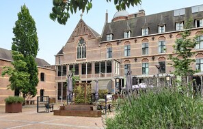 A historic building with a prominent tower, large windows, and outdoor seating areas. - Stunning home in Oud Gastel with WiFi (Oud Gastel)