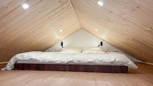 A bedroom with a sloped ceiling, wooden flooring, and a bed with white bedding. - 2 bedroom lovely home in Oud Gastel (Oud Gastel)