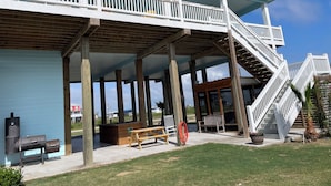 Ein überdachter Außenbereich mit Holzdeck, Grill und Bank.