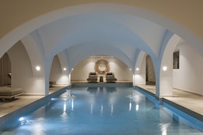 An indoor swimming pool with arched ceilings and two lounge chairs. - Nero Light-filled Suites (Santorini)