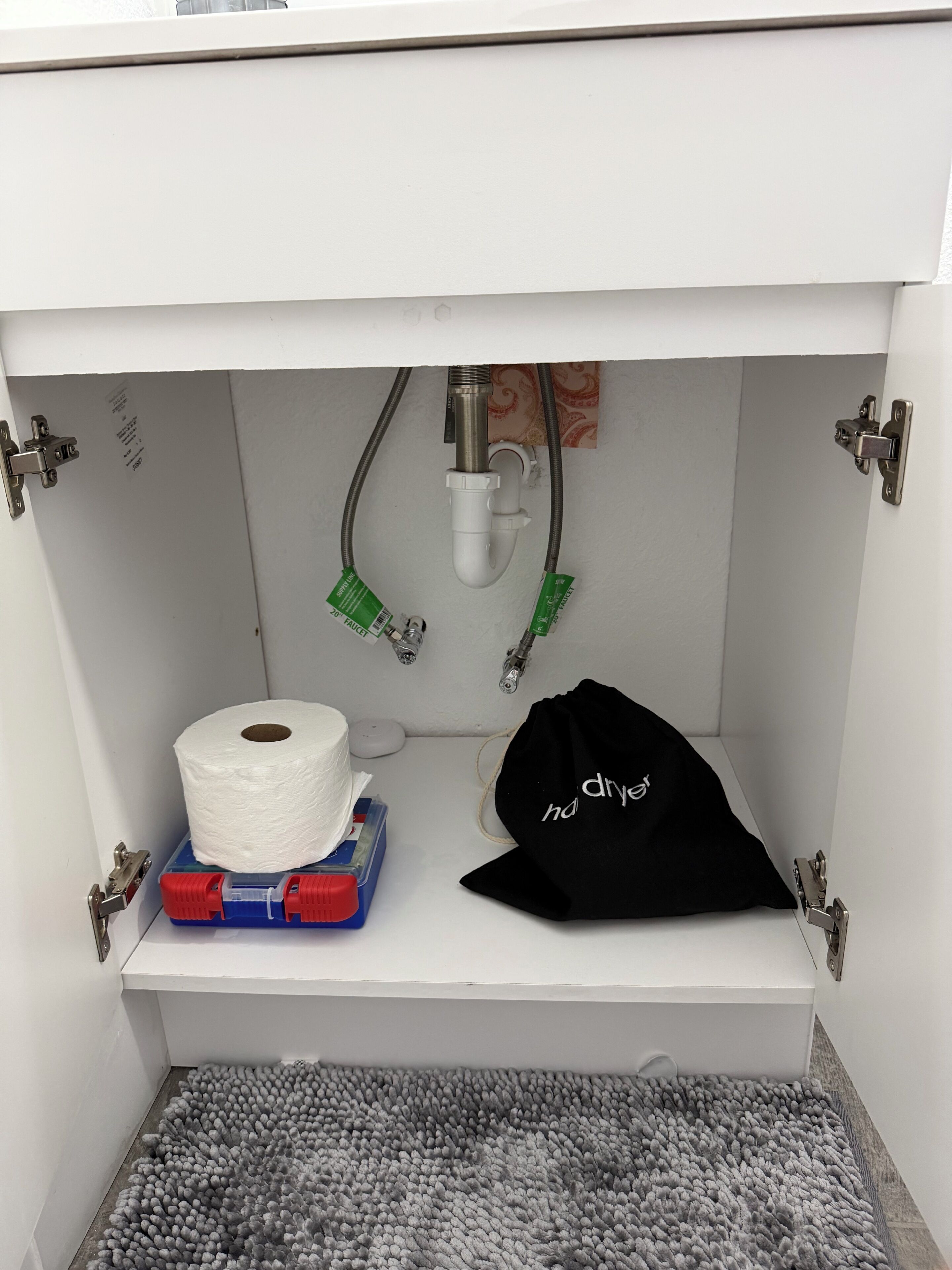 A bathroom with a toilet paper roll, a black bag, and a towel rack.