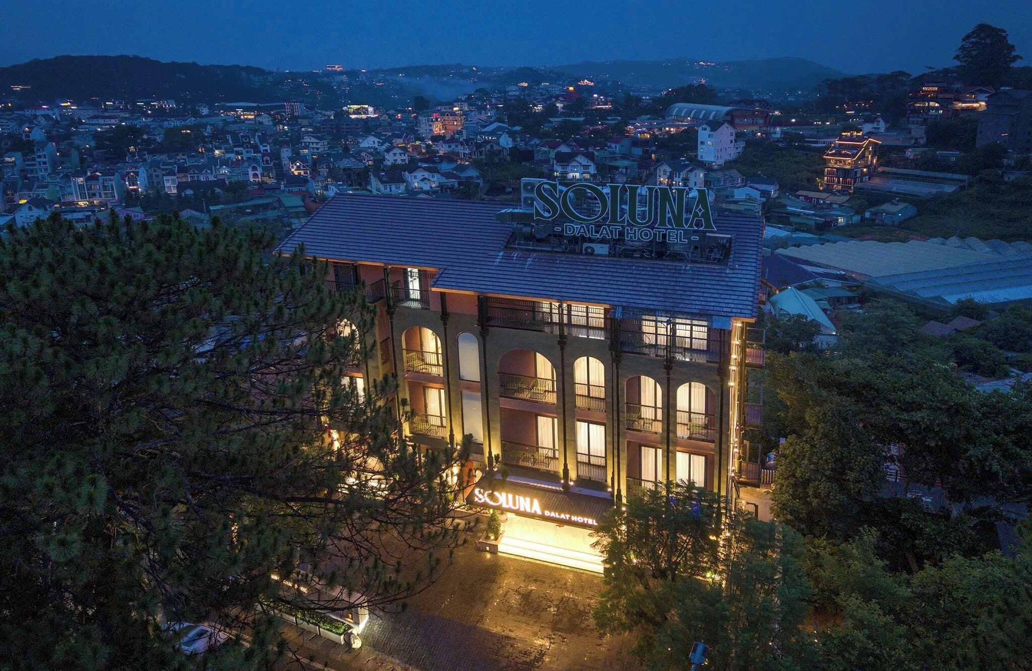 Un hotel con un cartel llamativo, varios balcones y vistas del pueblo circundante.