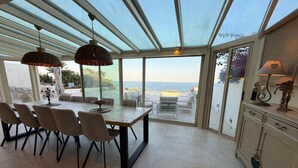 A dining area with a table and chairs, a glass ceiling, and a view of the sea. - 5-bedroom house, sea view, swimming pool (Fréjus)