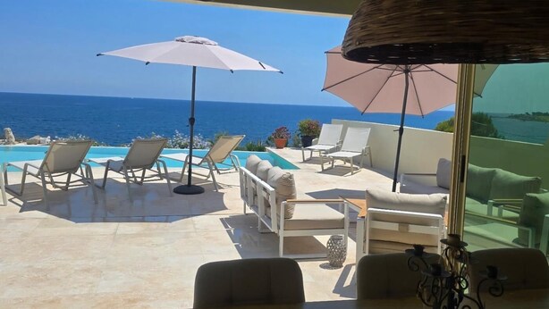 A terrace with a pool, lounge chairs, and umbrellas overlooking the sea. - 5-bedroom house, sea view, swimming pool (Fréjus)