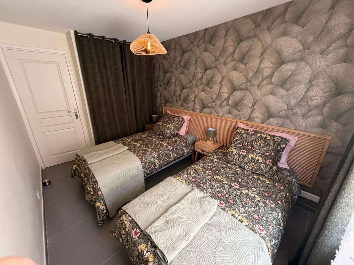 Et soveværelse med seng, to sengeborde, et natbord, en hængende lampe og en dør.