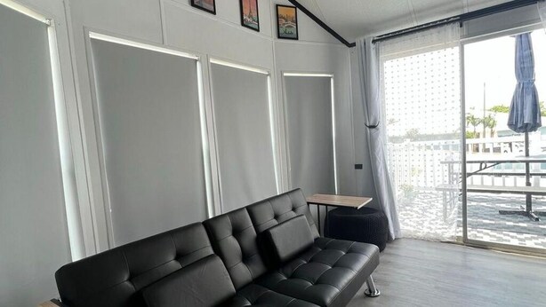 Een moderne kamer met een zwarte leren bank, een klein houten tafeltje en een groot raam met uitzicht op het water.