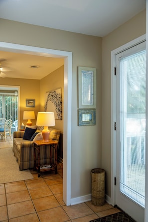 A living room with a sofa, two lamps, a wicker basket, and framed artwork on the wall. - Coastal Home on Wrightsville Beach on Harbor Island (Wrightsville Beach)