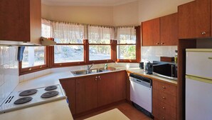 A kitchen with wooden cabinets, a stove, a sink, and a dishwasher. - Granite Garden Apartment - 2 Bedroom (Eukey)