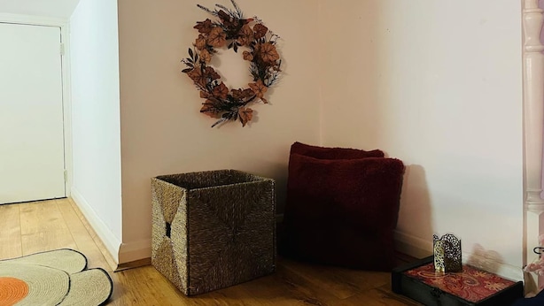 A corner room with a wooden floor, a woven storage box, a red cushion, and a decorative wreath on the wall. - 5 Minute Walk to St Paul s Cathedral (London)