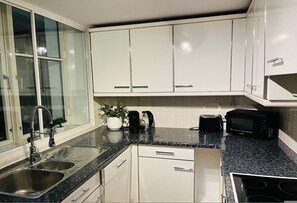 A modern kitchen with white cabinets, a granite countertop, stainless steel sink, and a black stove. - 5 Minute Walk to St Paul s Cathedral (London)