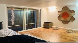 A bedroom with a bed, a sliding glass door, a wall-mounted decorative item, and a small basket. - 5 Minute Walk to St Paul s Cathedral (London)