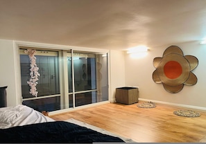 A bedroom with a bed, a sliding glass door, a wall-mounted decorative item, and a small basket. - 5 Minute Walk to St Paul s Cathedral (London)