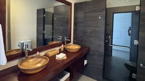 Ein modernes Badezimmer mit einem Holzkosmetikschrank, zwei Aufsatzwaschbecken, einem großen Spiegel und einem Deckenventilator.
