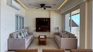 Ein modernes Wohnzimmer mit zwei Sofas, einem Couchtisch, einem Fernseher und einem Deckenventilator.
