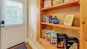 A wooden bookshelf with various board games and books. - The Peacock House - Vintage Downtown Charm (Ocala)