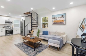 A modern kitchen with stainless steel appliances, a wooden dining table, and a spiral staircase.