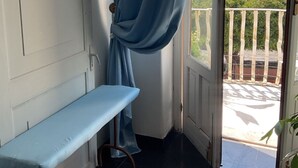 A room with a bench, a curtain, a door, and a view of a body of water and greenery. - Armonia sul mare (Syracuse)