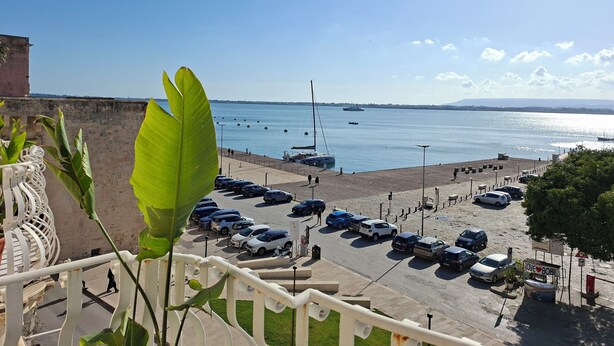 A coastal view with a parking lot, boats, and a clear sky. - Armonia sul mare (Syracuse)