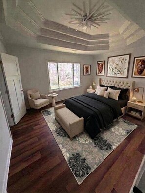 Ein Schlafzimmer mit einem großen Bett, einem Nachttisch, einem Sessel, einem Fenster und Bildern an der Wand.