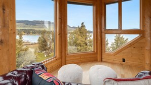 A wooden cabin with large windows, a leather couch, and ottomans.
