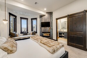 A bedroom with a large bed, a fireplace, a TV, and a sliding door. - New! Ski-In/Ski-Out Chalet | Chair 3 | Hot Tub | Slopes View | Sleeps 8 (Whitefish)