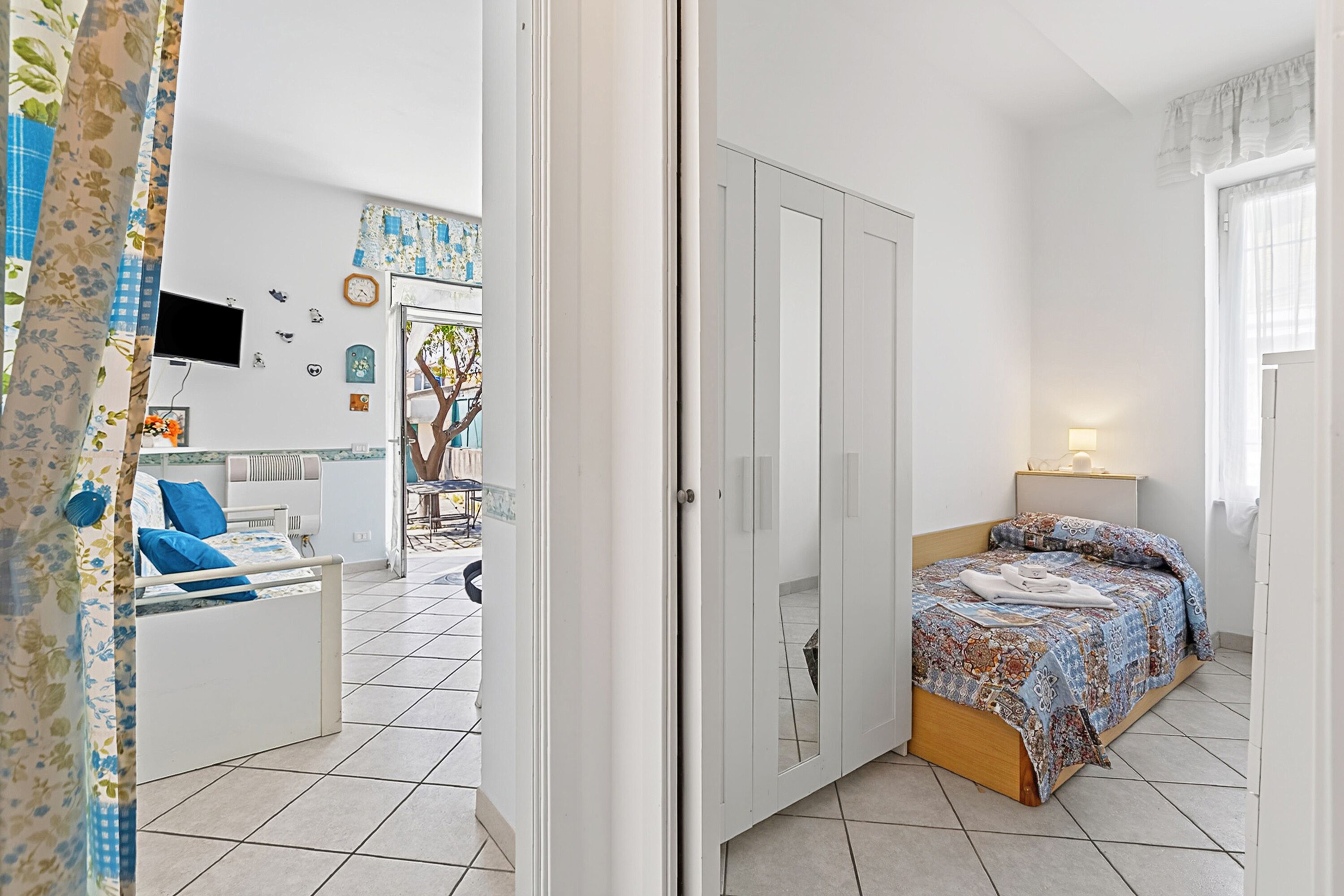 A bedroom with a bed, a wardrobe, a TV, and a bathroom visible through an open door.