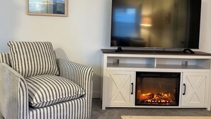 Una sala de estar con un sofá a rayas, un televisor de pantalla plana, una chimenea y un cuadro en la pared.