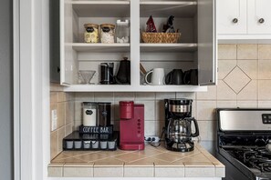 Een keuken met een koffiehoek, inclusief een koffiezetapparaat, een rode espresso machine en een bord met daarop 'Coffee Bar'.