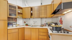 Een keuken met houten kasten, een wit aanrecht, een fornuis en een spoelbak.