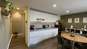 Une cuisine moderne avec des meubles blancs, un réfrigérateur rouge et un coin repas comprenant une table ronde et des chaises.
