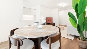 Et moderne spiseområde med et rundt marmorbord, træstole og en stor, grøn plante.