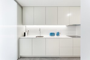 A modern kitchen with white cabinets, a stainless steel sink, a toaster, and a kettle. - GuestReady - Seaside retreat in Matosinhos (Matosinhos)