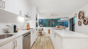 Eine moderne Küche mit weißen Schränken, einem eingebauten Geschirrspüler und einem großen Fenster mit Blick ins Freie.