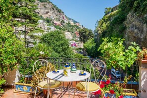 A terrace with a table and chairs, overlooking a hillside with buildings.