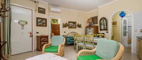 A room with wicker furniture, a dining table, and a bed with a floral bedspread.