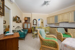 Una habitación con una mesa de comedor, sillas de mimbre, un sofá y un armario.