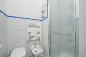 A bathroom with a toilet, bidet, and glass shower enclosure.