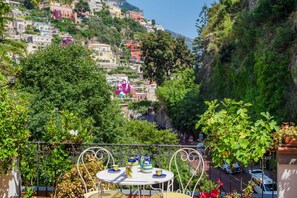 Un balcón con una mesa dispuesta para comer, con vistas a una colina con edificios de colores.