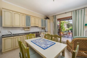 Cozinha com mesa de jantar, cadeiras e vista para o exterior.