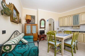 A cozy room with a bed, a dining table with chairs, a television, and a kitchen area. - Positano Elegant Terrace – Panoramic Home with Terrace in the Heart of Positano (Positano)