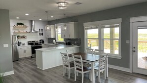 Una cucina moderna con mobili bianchi, un'isola centrale e luci a sospensione.