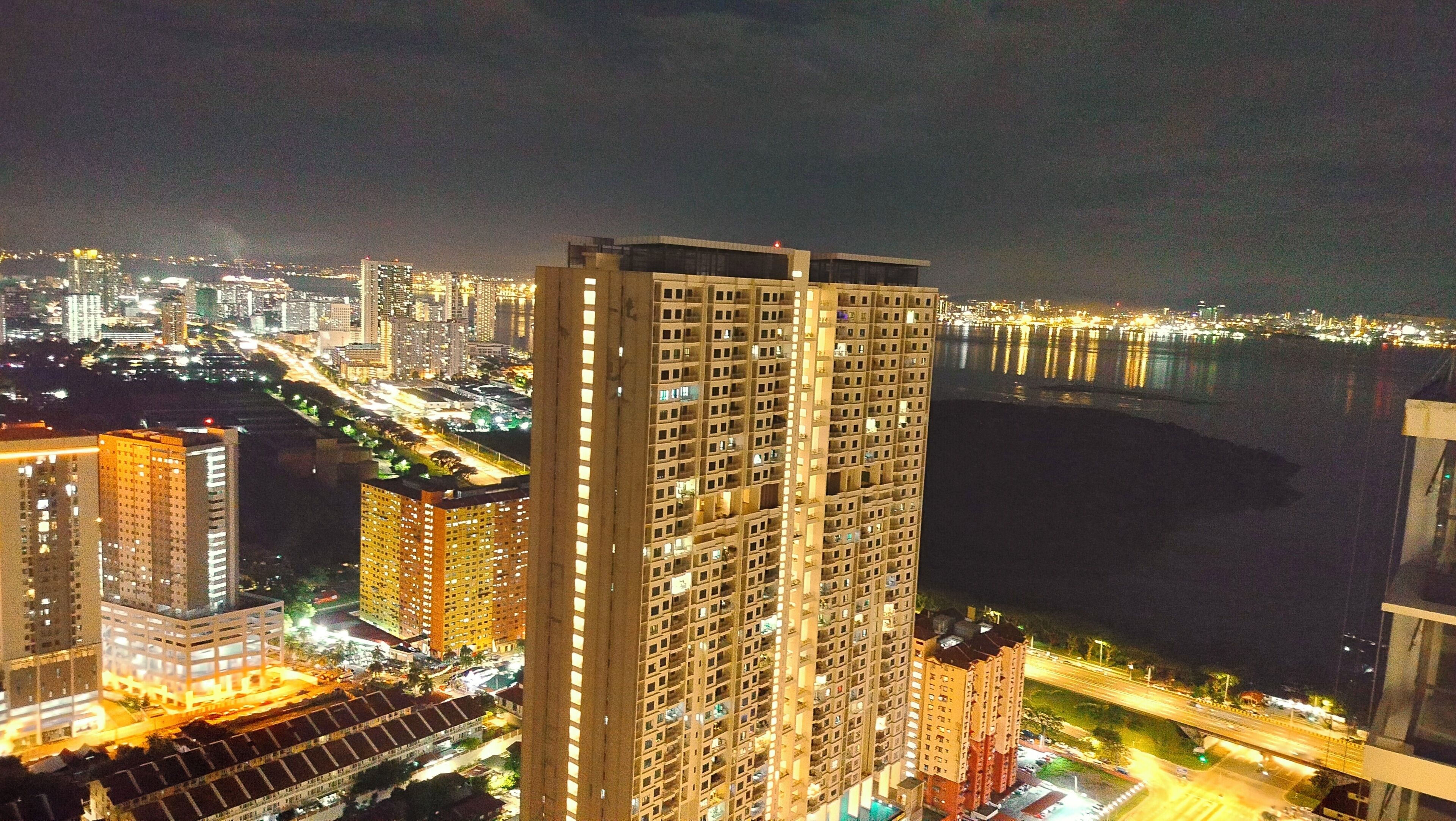 A high-rise building with multiple floors, large windows, and a view of a cityscape at night.